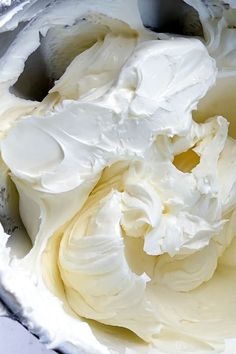 a metal bowl filled with white frosting on top of a counter