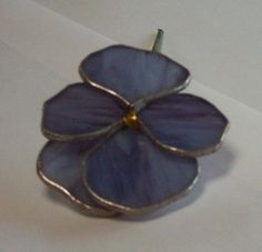 a blue flower brooch sitting on top of a white table next to a wall