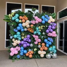 an outdoor display with balloons, flowers and other decorations on the side of a building