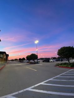 an empty parking lot with cars parked on the side and a street light in the distance