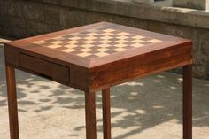 a wooden table with a checkerboard design on the top and drawer at the bottom