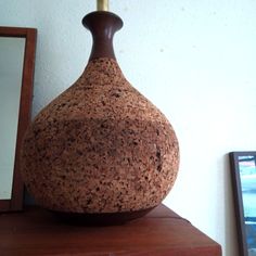 a brown vase sitting on top of a wooden table next to a mirror and framed photograph