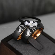 two wedding rings with horses on them sitting on top of a wooden box in front of a gray background