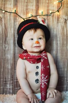 a baby wearing a hat and scarf with a snowman on it's chest