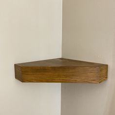 a wooden shelf mounted to the side of a wall next to a white painted wall