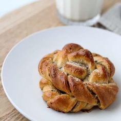 a white plate topped with two braided breads next to a glass of milk