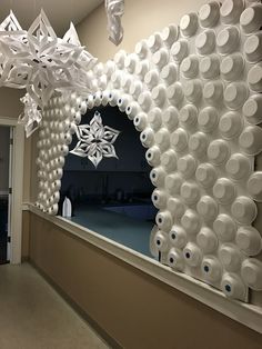 a large mirror made out of cups and paper snowflakes