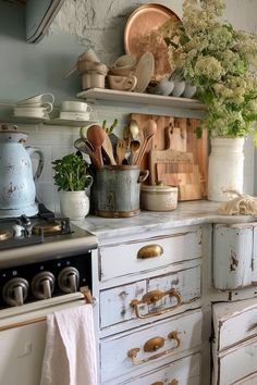 an old fashioned kitchen with pots and pans on the stove top, white cabinets and drawers