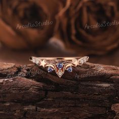 a gold ring with blue and white stones sits on top of a piece of wood