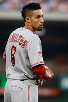 a baseball player standing on the field with his hands in his pockets and looking off into the distance