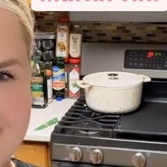 a woman standing in front of an oven smiling at the camera and looking into the camera