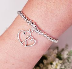 This is a beautiful handmade stretch bead  stacking bracelet that is lovingly made to a high standard using 4 & 5 mm round silver-plated beads that are highlighted with 5mm antique silver daisy spacer beads and then finished perfectly with a silver double openwork heart charm.  This bracelet can also be bought as part of a set. Please see my other shop items for details of sets this bracelet can be bought with. Perfect gift for someone special. Or maybe a a treat for yourself 🙂 Bracelets are ma Adjustable Beaded Bracelets With Heart Charm For Wedding, Heart-shaped Wedding Beaded Bracelet, Adjustable Heart-shaped Beaded Bracelet For Anniversary, Handmade Stretch Bracelet As A Gift, Adjustable Heart Beads Bracelets For Anniversary, Adjustable Heart Beads Bracelet For Anniversary, Silver Stretch Bracelet With Heart Beads As Gift, Heart Beads Stretch Bracelet For Friendship, Mother's Day Adjustable Heart Beads Charm Bracelet