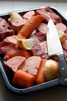 a tray filled with meat and vegetables next to a knife