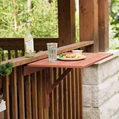 a plate of food and drink on a wooden table outside with trees in the background