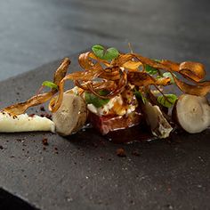 a plate with some food on it sitting on top of a black table next to a cup