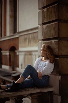 a woman is sitting on a ledge outside