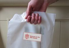 a person holding a white bag with the words welcome to the family on it