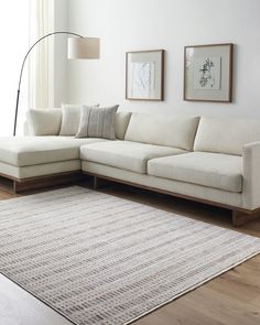 a white couch sitting on top of a wooden floor next to a lamp and rug