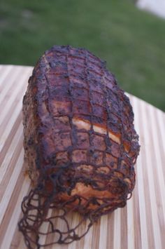 a piece of meat sitting on top of a wooden table next to a green field