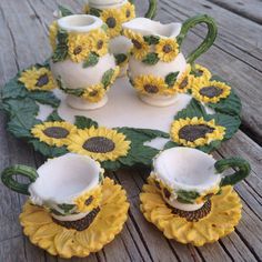 there are sunflowers on the table with tea cups and saucers in them