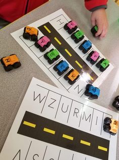 a young child playing with cars and blocks on the table in front of a sign