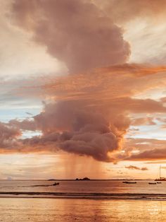 the sun is setting over the ocean with sailboats in the water and clouds above