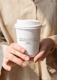 a woman holding a coffee cup with the words your design on it in her hands