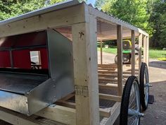 an outdoor bbq grill with wheels attached to the side and a picnic table behind it