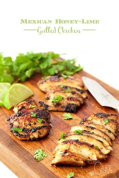 grilled chicken cut up on a cutting board with cilantro and limes