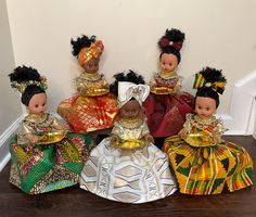 five african dolls sitting on top of a wooden floor next to each other in dresses