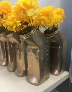 three metal vases with yellow flowers in them