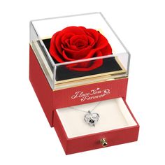 a red rose in a glass box with a heart charm on the bottom and an open ring