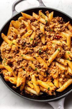 pasta with meat and sauce in a skillet on a marble counter top, ready to be eaten