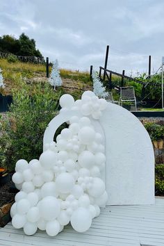 white balloons are floating in the air next to a large sculpture that looks like an arch