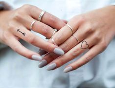 a woman's hands with three rings and two hearts on her fingers, both holding each other