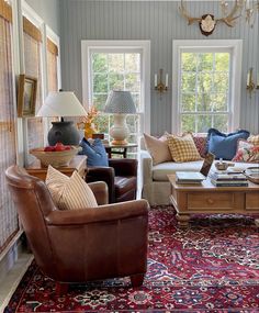 a living room filled with lots of furniture and pillows on top of a red rug