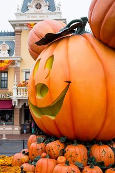 pumpkins are stacked on top of each other in front of a building with a clock tower