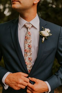 a man in a suit and flower boutonniere is holding his hands together