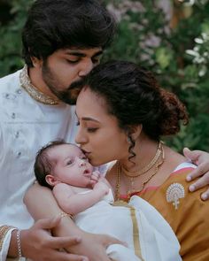 a man and woman holding a baby in their arms