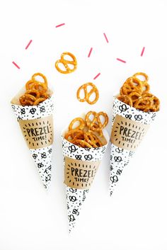 three cones filled with pretzels sitting on top of each other next to donuts