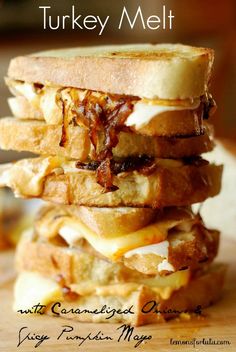 a stack of toasted sandwiches sitting on top of a wooden cutting board with bacon and cheese