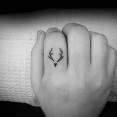 a woman's hand with a small deer head tattoo on it