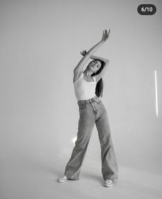 a woman standing in the middle of a white room with her arms up and legs crossed