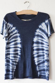 a blue and white tie - dye shirt hanging on a hanger against a wall