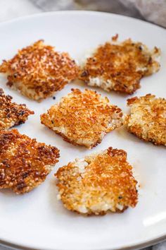 several pieces of chicken on a white plate with parmesan sprinkles