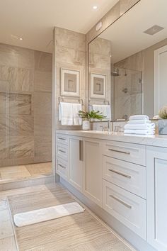 a large bathroom with white cabinets and marble counter tops, along with a walk in shower