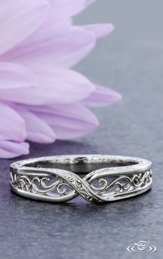 two wedding rings sitting next to a purple flower