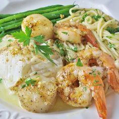 a white plate topped with shrimp, pasta and asparagus