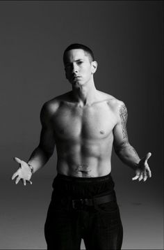 a shirtless man with his hands out in front of him, posing for a black and white photo