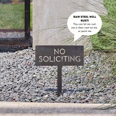 a no soliciting sign sitting on top of gravel